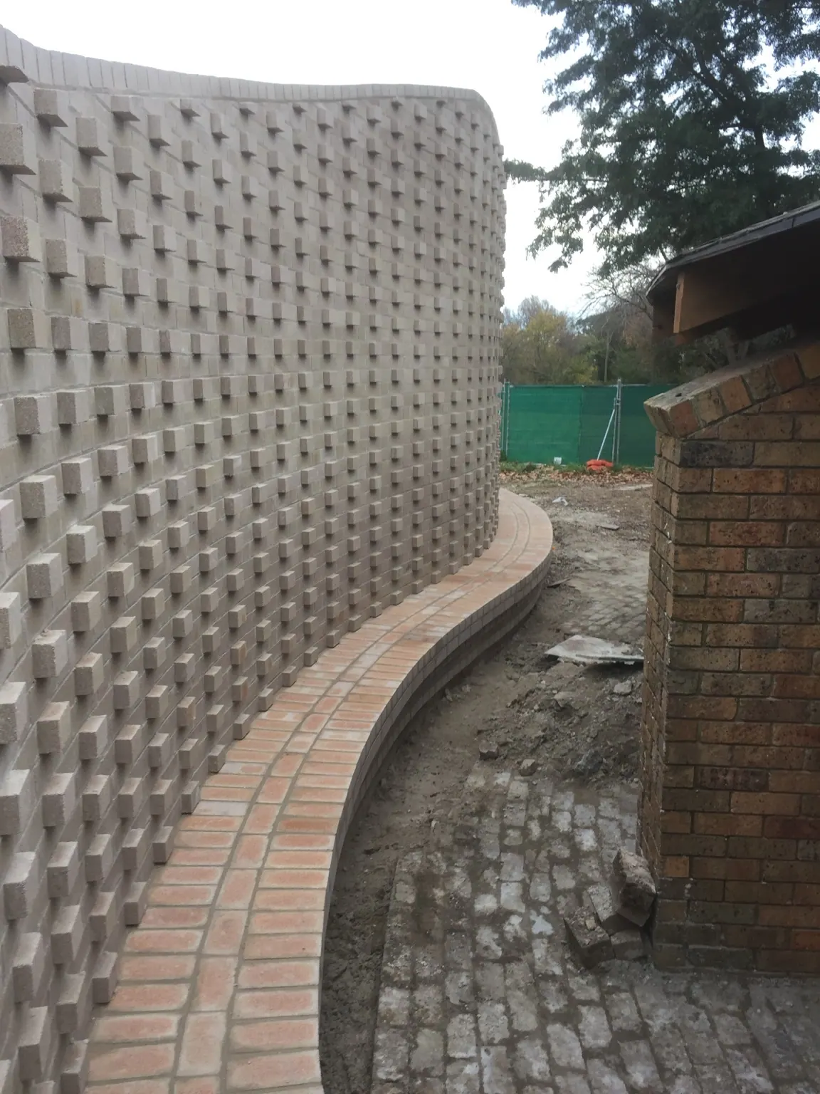Curved masonry wall with projecting blockwork texture